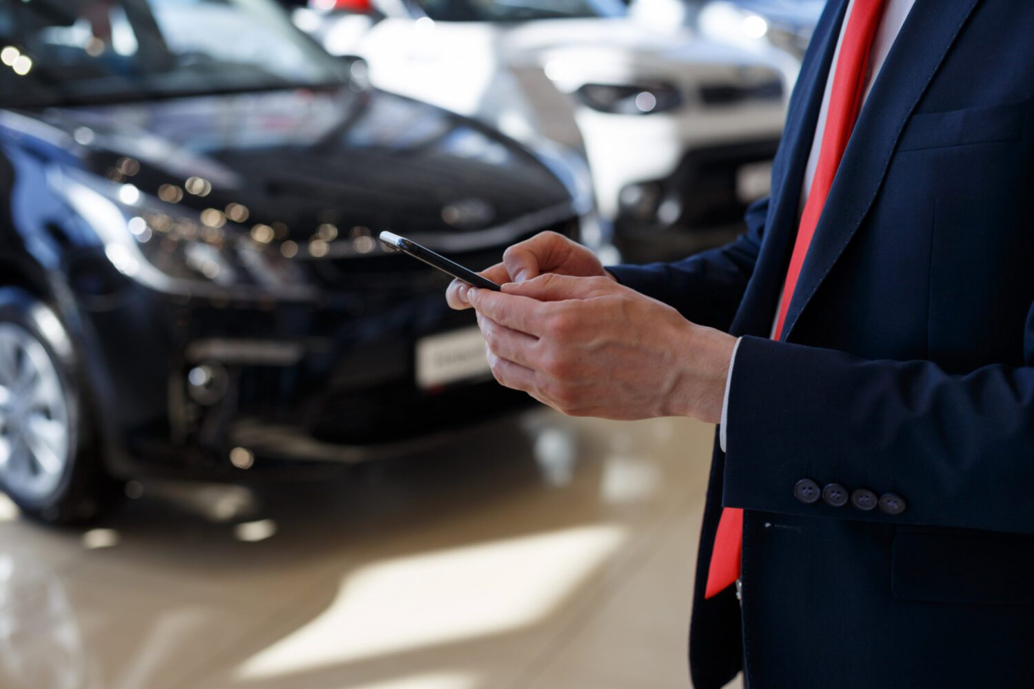 Man using mobile smartphone at dealer showroom.