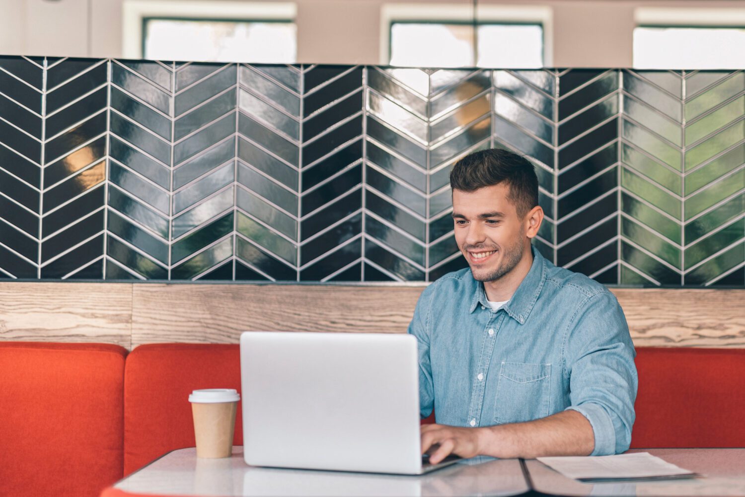 Cheerful man smiling and working on his laptop in cafe