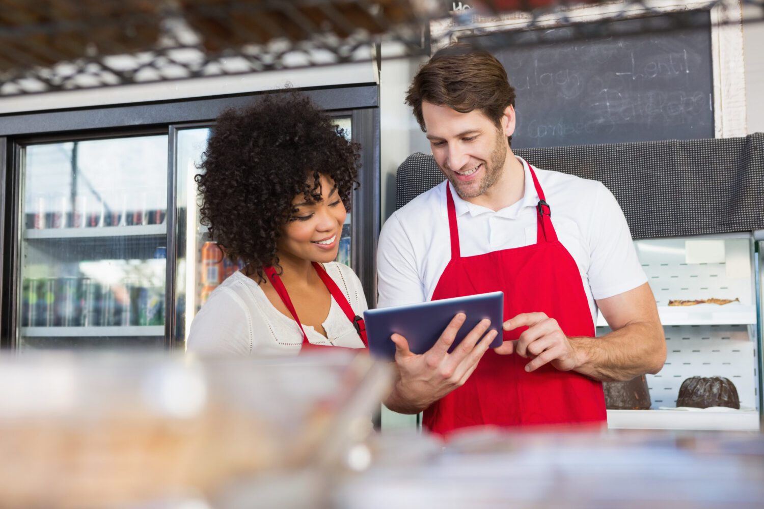 Colleagues in red apron using tablet at the bakery