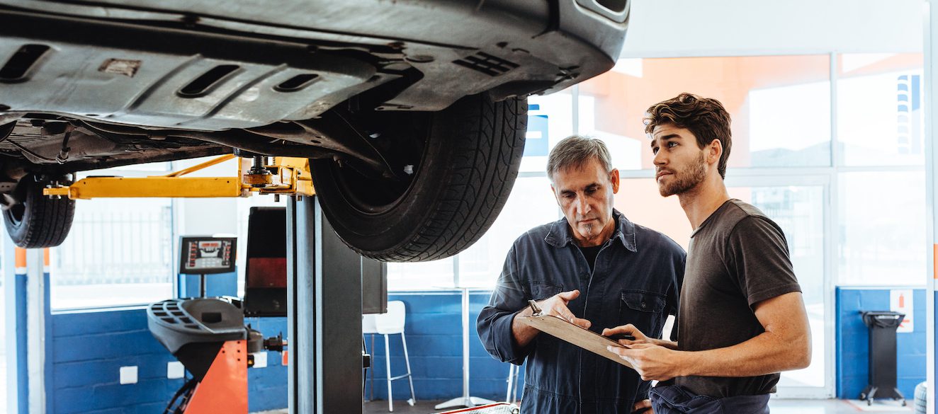 Auto mechanics making a list of repairs on car in service station Glaminator Beauty